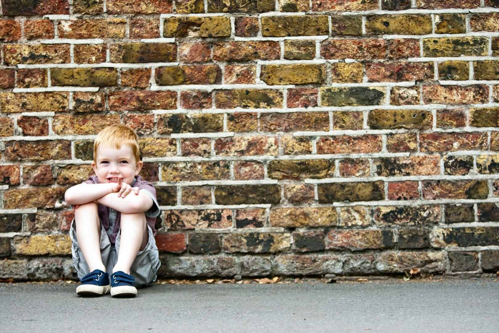 a young boy is photographed against a brick wall in greenwich, london