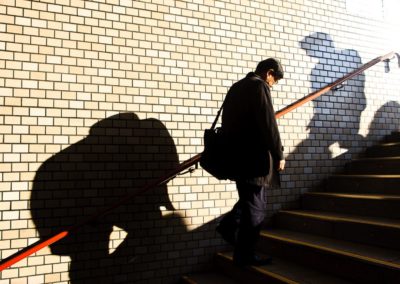 the shadows of workers are cast against the wall of a subway station in japan