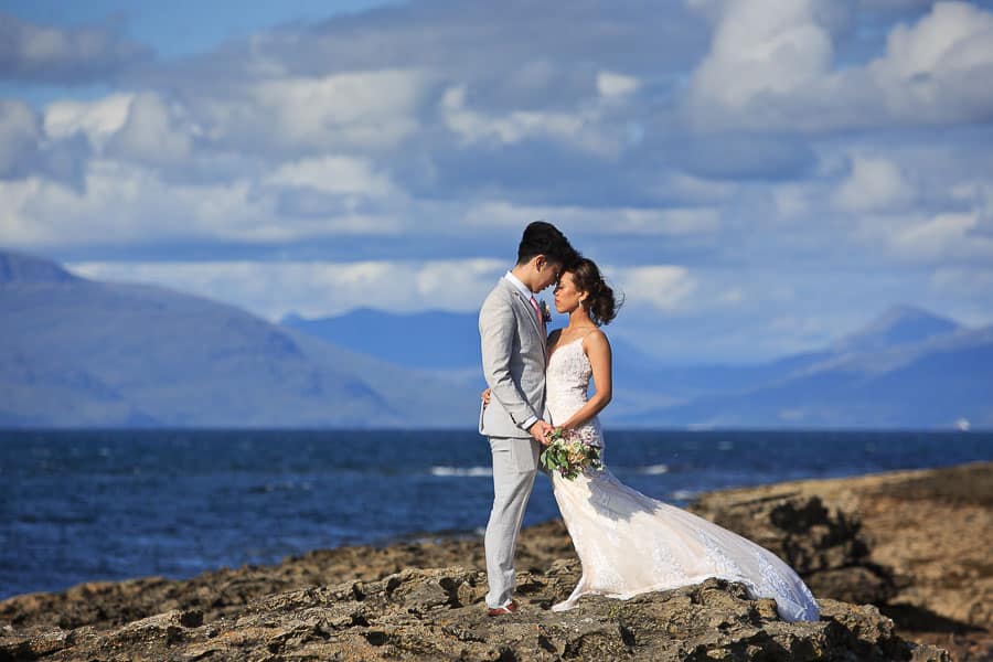 An asian bride and groom pose for their pre wedding photo shoot on a beach in scotland